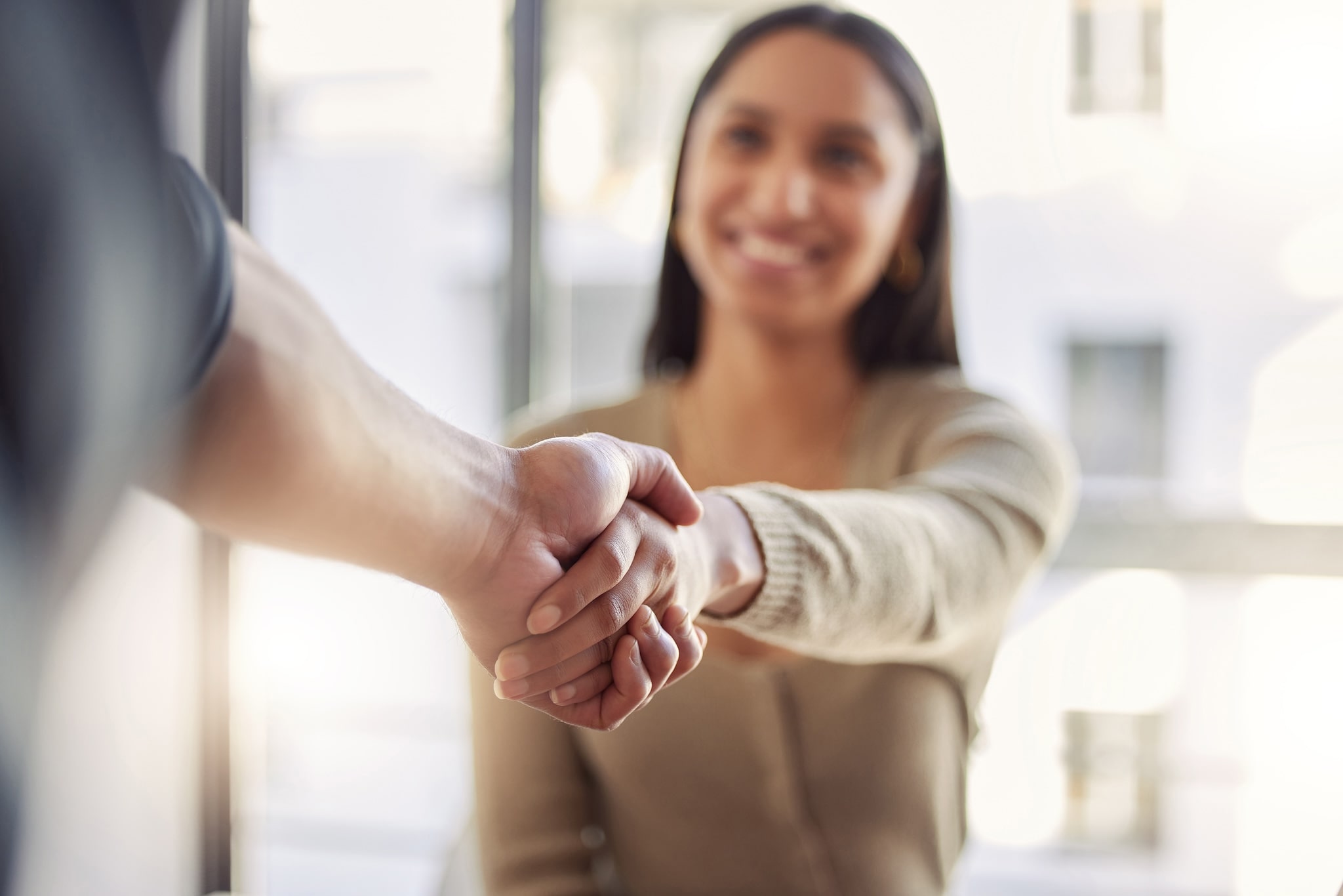 A young woman shaking someone's hand and smiling